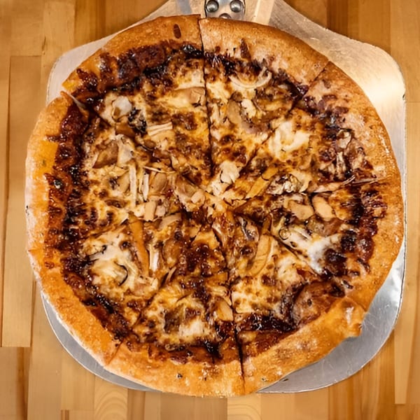 A whole Five Bros Pizza with caramelized onions and mushrooms on a metal pizza peel.