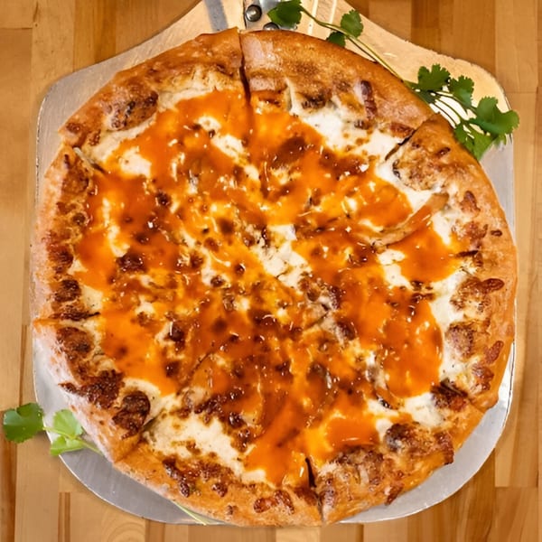 A Five Bros Pizza with white cheese and a generous drizzle of orange sauce on a wooden table.